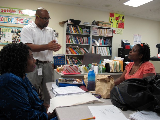 Uzelea Evans, right, and TKTK TKTK, left, talk with GED teacher Travis McGinnis at Metropolitan Ministries. The GED is changing in January, and McGinnis said his students have been planning since September whether to take the old test or the new GED.
