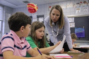 Laurie Langford, a second grade teacher at West Defuniak Elementary, helps two students look for evidence in a reading passage about public sector jobs.