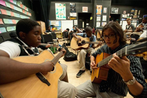 Leslie Augustin, 13, an eighth-grade student in the guitar class, gets individual attention from Jonathan De Leon, founder of the guitar program at the school.