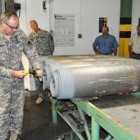 Lt. Gen. James Pillsbury removes the rear casing plate of a bomb at the McAlester Army Ammunition Plant.