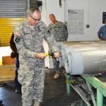 Lt. Gen. James Pillsbury removes the rear casing plate of a bomb at the McAlester Army Ammunition Plant.