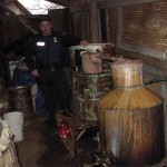 Capt. Joe Daniels, a special agent in charge of the state Alcoholic Beverage Laws Enforcement Commission, stands near an illegal whiskey still found in a barn during a raid on a southeastern Oklahoma home.