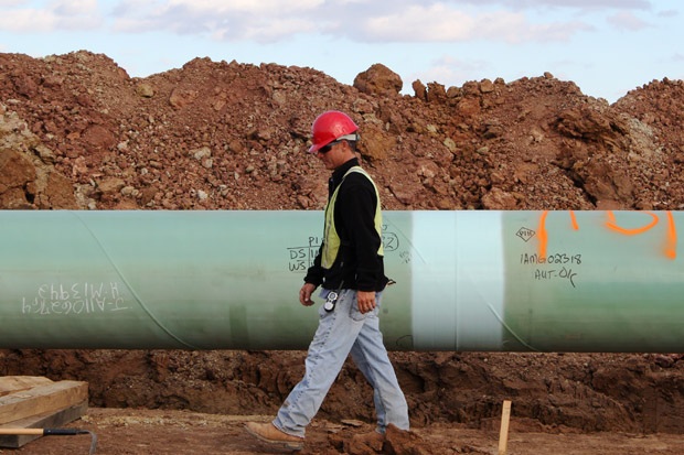 A worker inspects a segment of the Keystone Pipeline before it's lowered into a trench near Stroud, Okla. 