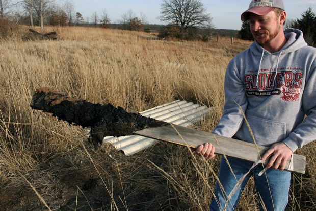 Tyler Lane pulls up a wooden marker covered with oily sludge in the land behind his Bristow home. Lane uses stakes and rope to keep his two children out of the oiliest, most dangerous parts of his land, which sits atop the abandoned Wilcox Refinery, Oklahoma’s newest Superfund site. 