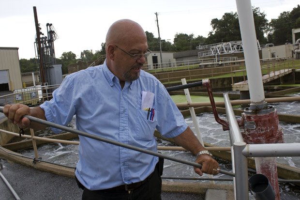 Tom Myers, superintendent of the new wastewater treatment plant in Siloam Springs, Ark., holds a sample of treated water that will be discharged into Oklahoma's Flint Creek.