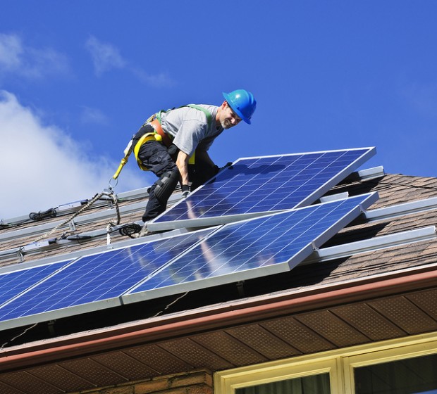A worker installs a rooftop solar panel.