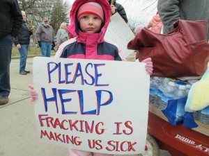 Skylar McEvoy holds up a sign at a rally in Butler, Pa. She and her family moved after they say fracking polluted their water. Her mother Kim says the DOH was no help.