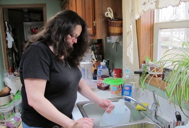Kim McEvoy fills up a jug of water at her former home in Butler County in this 2012 file photo. She says after natural gas drilling began, her water turned grey and black. Then, she began experiencing strange physical symptoms.