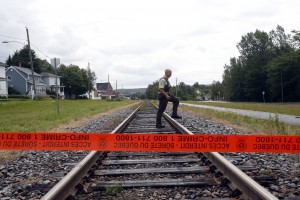 A Quebec Provincial Policeman crosses the railway tracks inside the exclusion zone in the town of Lac Megantic, Quebec.  Hundreds of residents were evacuated from their homes when a runaway train loaded with crude oil exploded on July 6. 