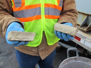 A worker breaks apart a brick of solid material left over from treating frack water. The solid material, which may contain radioactive elements, gets disposed of in landfills.