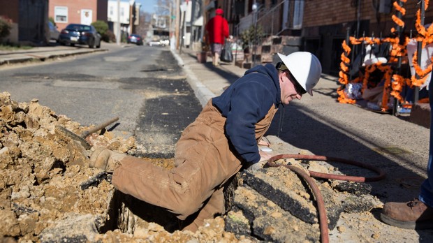 Michael Groves, PGW Senior Pipe Mechanic climbs out of a hole on Van Pelt Street after inspecting a new main gas line in North Philadelphia. 