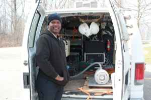 Mark Omara stands in front of a van outfitted with sensors to record methane emissions in real time.