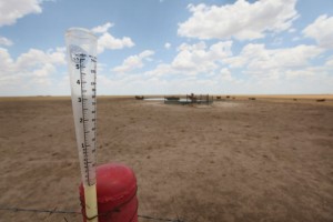 An empty rain gauge is strapped to a fence post on the edge of a pasture this summer near Canadian, Texas