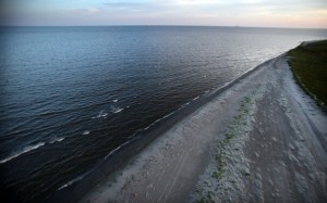 The sun sets waves wash up from the Gulf of Mexico onto the beach April 13, 2011 in Isla Grand Terre, Louisiana. T
