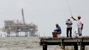 People fish with an oil rig in the background April 18, 2011 in Dauphin Island, Alabama.