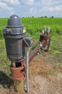 A motorized pump draws aquifer water up to the surface to irrigate the rice crop in the background. 