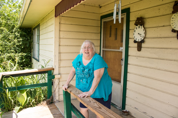 Susan Holmes stands on the front porch of her home in Bokoshe, Okla.