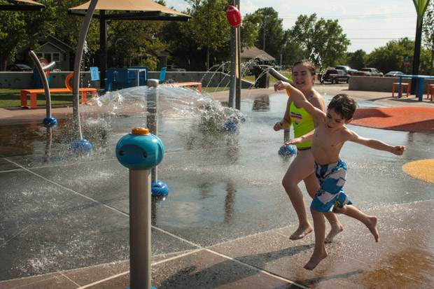 Olivia and Carter Kempen playing on a splash pad in Edmond, Okla.
