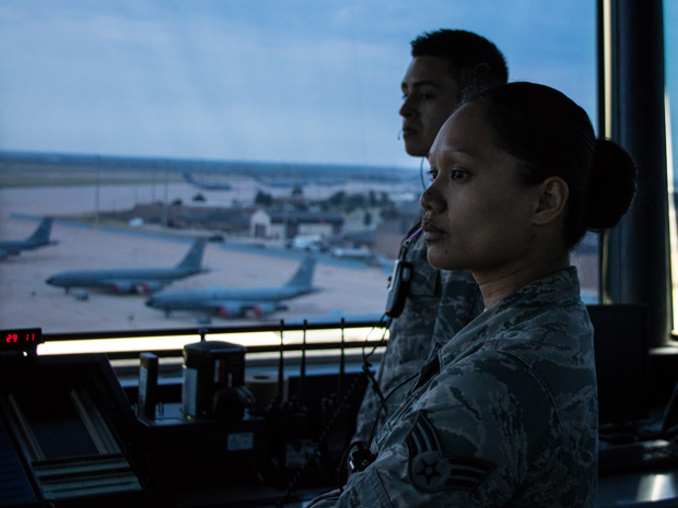 Trainees in the control tower at Altus Air Force Base watch as a C-17 cargo plane taxis to the runway.