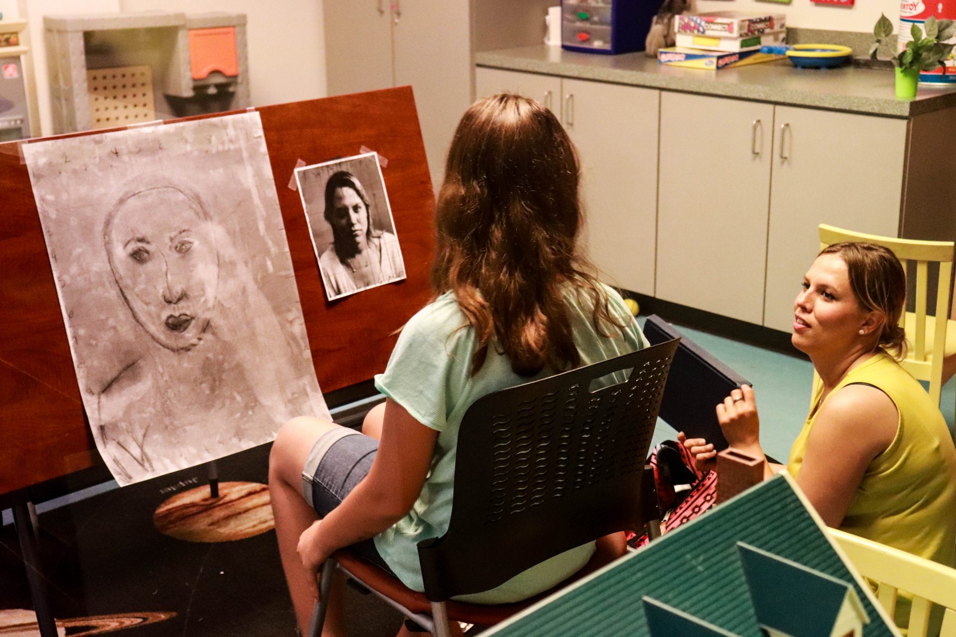 Sarah Sinkinson and her daughter collaborate on a charcoal drawing in a visitation room at Women in Recovery.