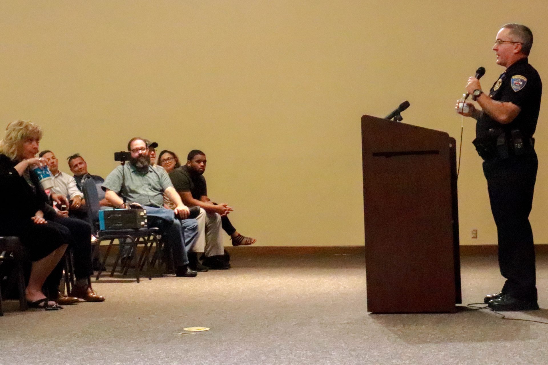 An Edmond police officer stands at a podium and answers audience questions inside an auditorium.