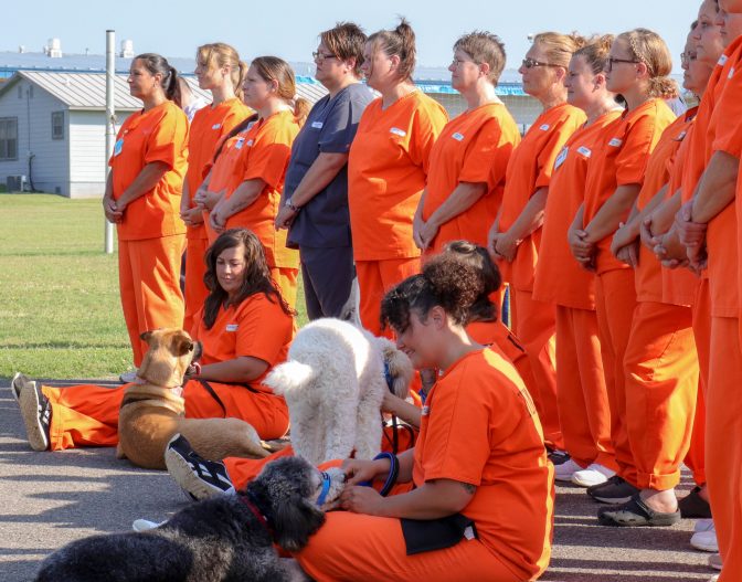 Women incarcerated at Mabel Bassett Correctional Center attend a ceremony commemorating a dog training program at the prison.