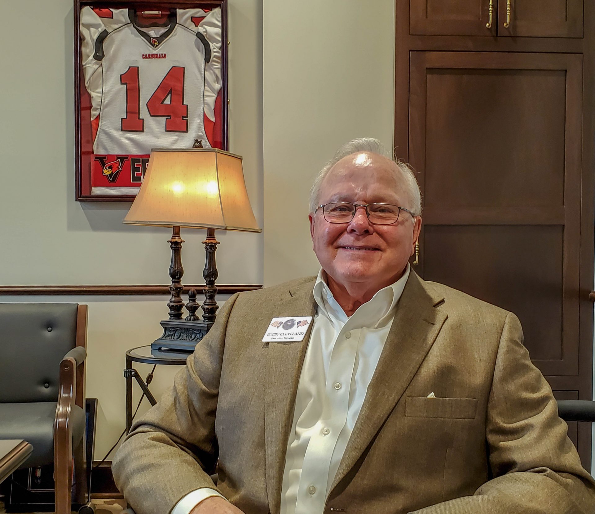 Bobby Cleveland sitting in an office at the state Capitol. A framed Arizona Cardinals jersey hangs behind him.