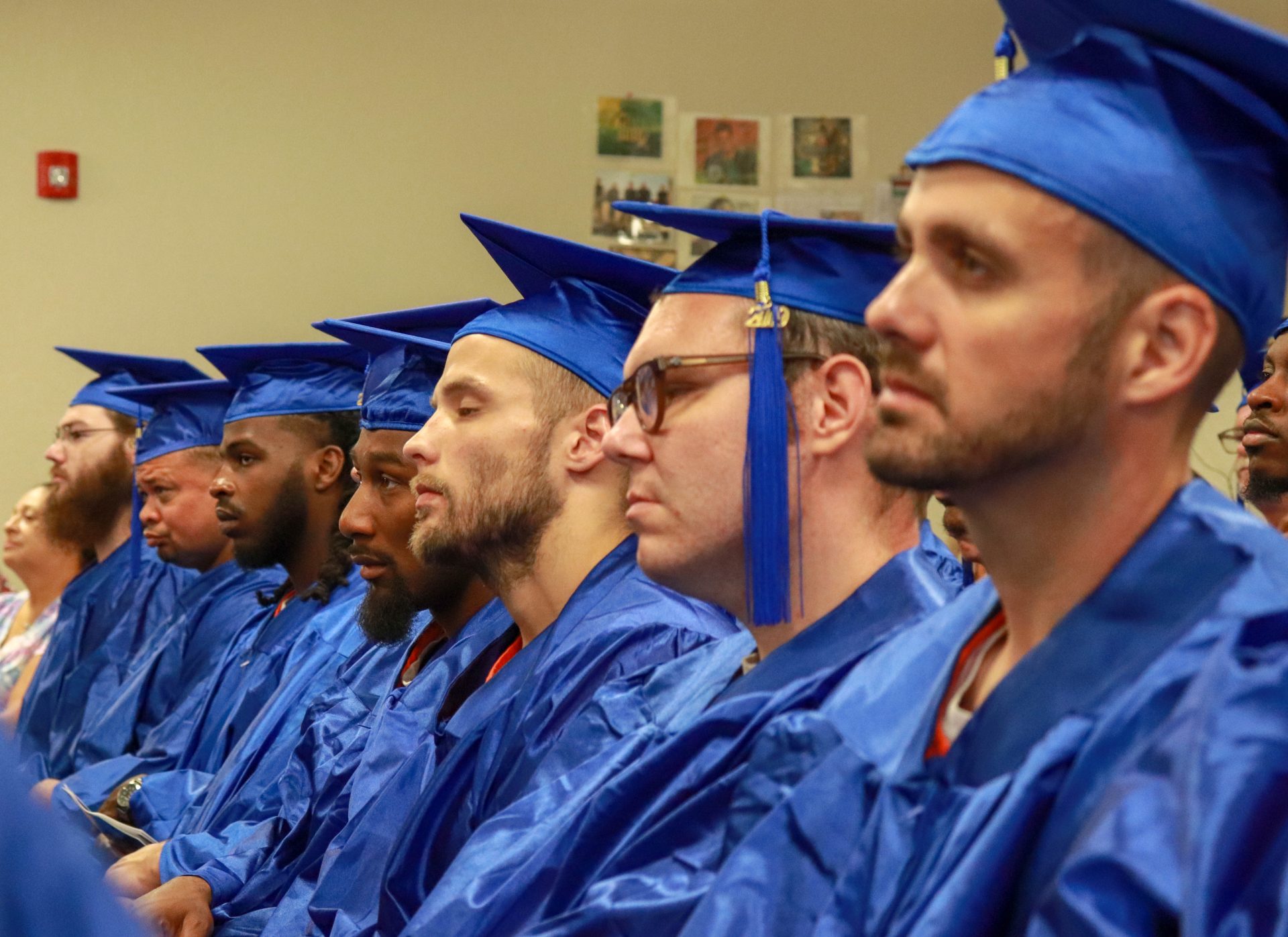Prisoners in blue graduation gowns sit during graduation ceremony.