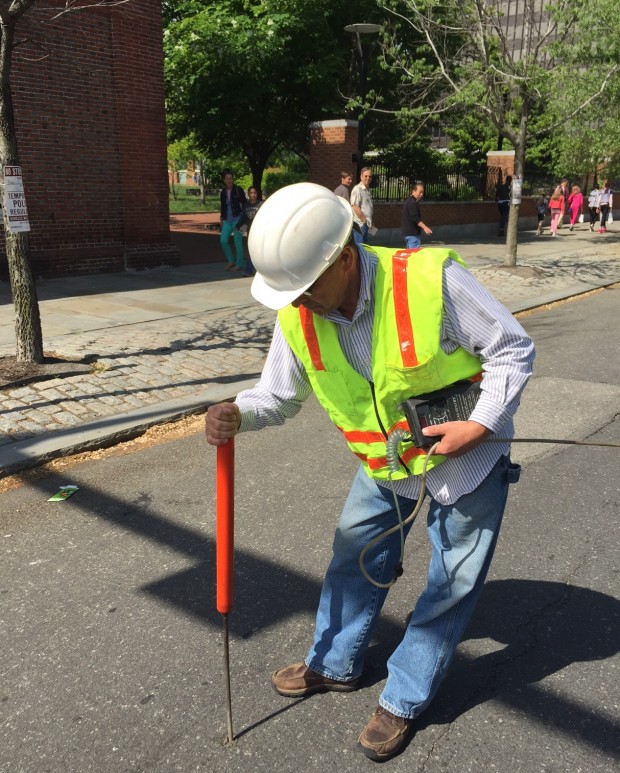 Bob Ackley uses a bang bar to drill a small hole in the street to check for gas leaks.