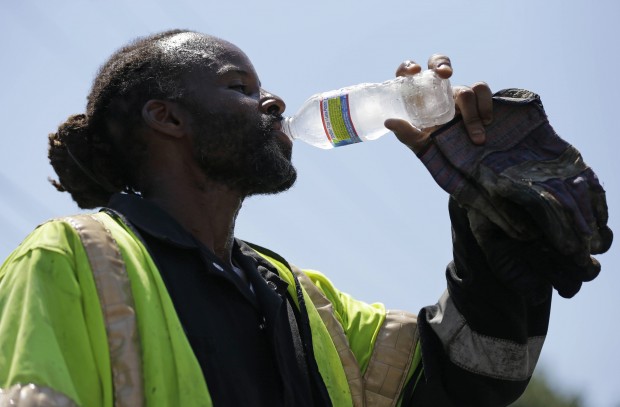 A paving crew member takes a drink of water during a record-breaking heat wave, July 6, 2012, in Philadelphia. is among Pennsylvania cities facing an increase in high temperatures and humidity caused by climate change, report warns.