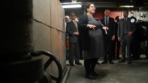 Emily Schapira, executive director of the Philadelphia Energy Authority, talks to reporters in front of an old boiler in the basement of Lankenau High School, an example of the kinds of improvements that could be made under the Energy Pilot Project. 