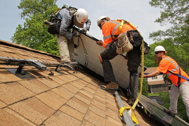 Workers from Solar States (from left) Patrick Whittaker, Rida Bouharoun, and Dennis Hajnik, install solar panels on the roof of a home in Bryn Mawr. (Emma Lee/WHYY)