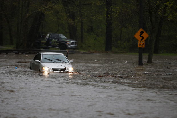 A man waves for a tow truck after getting swamped trying to cross a flooded section of the Cobbs Creek Parkway, Wednesday, April 30, 2014, in Philadelphia. Cobbs Creek and Darby Creek merge in the Eastwick section of Philadelphia where flooding is expected to get worse due to rising sea levels.