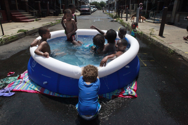 File photo: Michael Hall, 2, pulls down the edge of the pool while others swim on Wednesday, June 20, 2012, in Philadelphia. Climate change is expected to bring hotter weather to the state, which may mean subsidized air conditioning in the future.