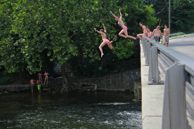 Teenagers take turns jumping into the Musconetcong river just below the Asbury Mill Dam. (Emma Lee/WHYY)