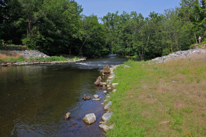 Piles of rock mark the spot where the Hughesville Dam once stood on the Musconetcong River. (Emma Lee/WHYY)