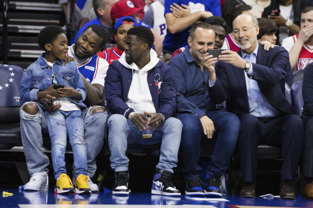Rapper Meek Mill, center left, looks on with his son, left, and actor Kevin Hart, center, as 76ers' co-owner Michael Rubin, center right, looks at Pennsylvania Gov. Tom Wolf's phone, right, during the first half in Game 5 of a first-round NBA basketball playoff series between the Miami Heat and the Philadelphia 76ers, Tuesday, April 24, 2018, in Philadelphia. The 76ers won 104-91. (AP Photo/Chris Szagola)